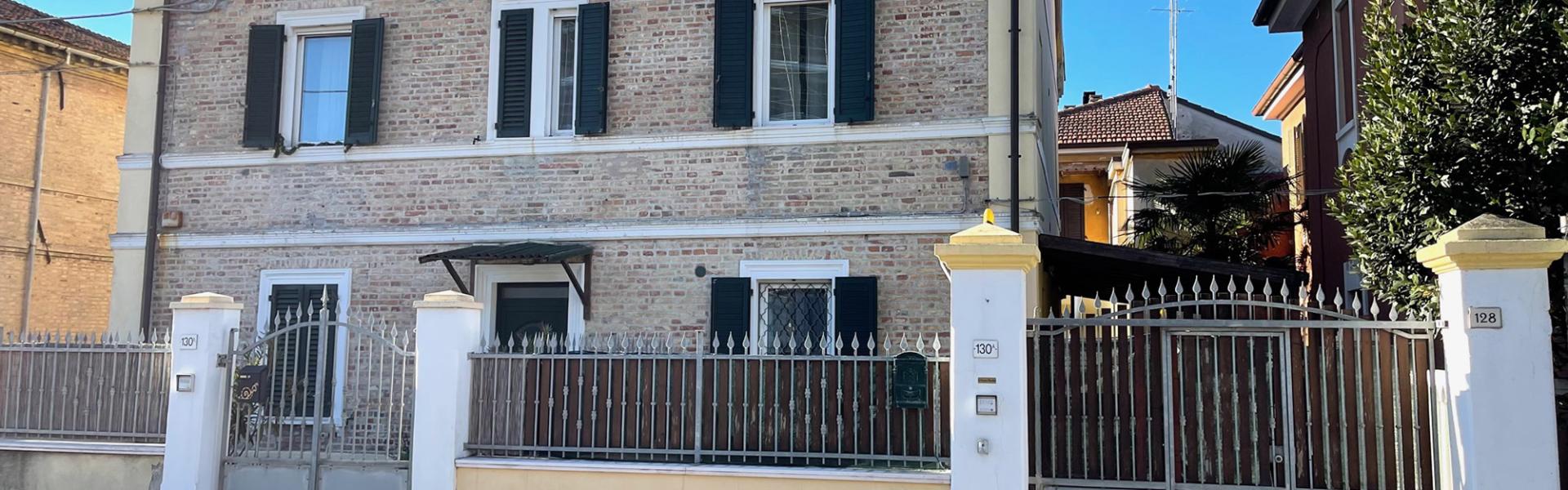 Casa in mattoni con persiane verdi e cancello in metallo.