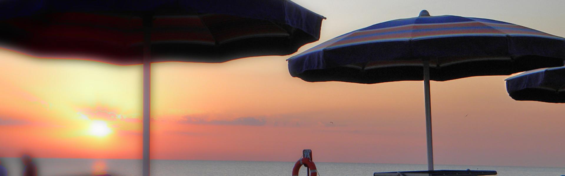 Sunset on the beach with empty loungers and umbrellas.